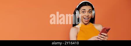 A vibrant woman smiles widely while listening to music on her phone. Stock Photo