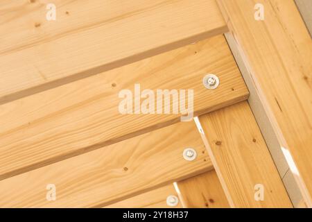 Close-up view of wooden beams and fasteners showcasing quality craftsmanship in outdoor decking during daylight. Stock Photo