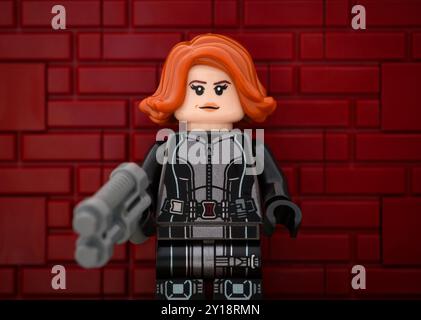 Tambov, Russian Federation - August 23, 2024 Portrait of Lego Black Widow minifigure with a gun against red brick wall background. Stock Photo