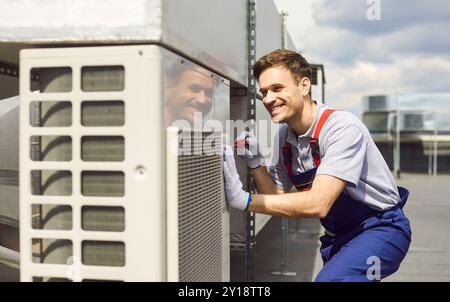 Young repairman installing and repairing ventilation system and air conditioner on the rooftop. Stock Photo