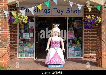 Front view of Ducklings Toy Shop Marlborough entrance with a large Playmobil princess figure standing outside and colorful decoration bunting above. Stock Photo