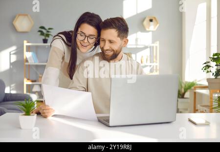 Young couple using laptop, checking financial documents at home Stock Photo