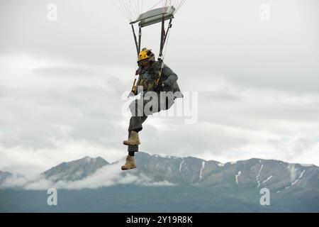 An Alaska Air National Guard pararescueman from the 212th Rescue Squadron lands after conducting airborne operations at Malemute Drop Zone at Joint Base Elmendorf-Richardson, Alaska, July 9, 2024. The Guardsmen of the 212th RQS and the 3rd Air Support Operations Squadron tactical air control party special warfare Airmen conducted joint airborne training to maintain the pararescuemen’s proficiency in conducting full-spectrum personnel recovery to include both conventional and unconventional rescue operations and the TACP’s to direct lethal and nonlethal joint firepower whenever necessary. (U.S. Stock Photo