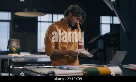 Indian business man arabian businessman decorator male tailor fashion designer couturier multitasking work talking mobile phone with client writing Stock Photo