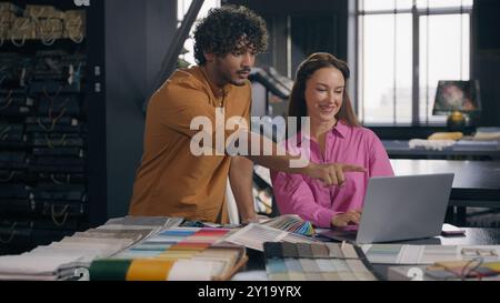 Multiracial business coworkers male female fashion designers work laptop discuss design project in atelier Arabian Indian man customer Caucasian woman Stock Photo