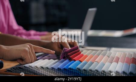 Close up hands fashion designer tailor choose textile samples cloth fabric collection. Cropped shot unknown man choosing material color for design Stock Photo