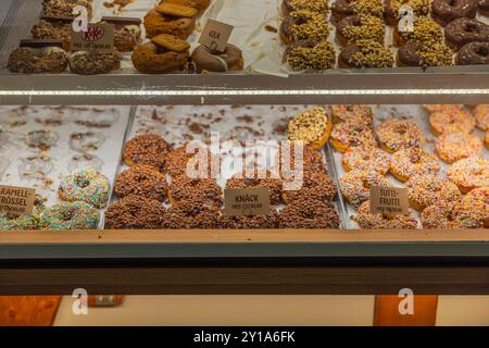 Kiosk display featuring variety of colorful donuts, including fruity, caramel and cola flavors. Sweden. Uppsala. Stock Photo