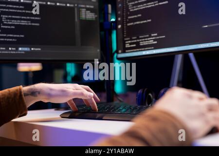 Developer typing code on computer to futureproof company network from downtimes and unexpected system failures. Man deploying programming script increasing data security, close up shot Stock Photo