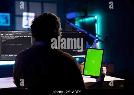 Cybersecurity expert using isolated screen tablet to look for security vulnerabilities and injected malware. Programmer installing fortified code on mockup portable device to prevent cyber attacks Stock Photo