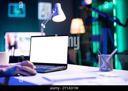 Closeup of person using a laptop showing isolated copyspace mockup template. An individual utilizing an electronic device on the table that is displaying a blank white screen. Stock Photo