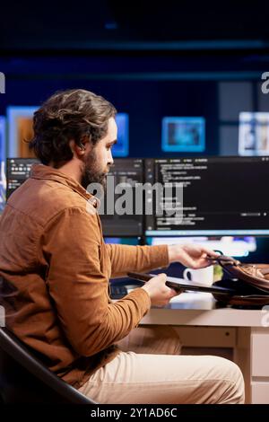 Man packing laptop after finishing doing software quality assurance and reading source code. Developer placing notebook in backpack after inspecting coding on desktop PC and finding all issues Stock Photo