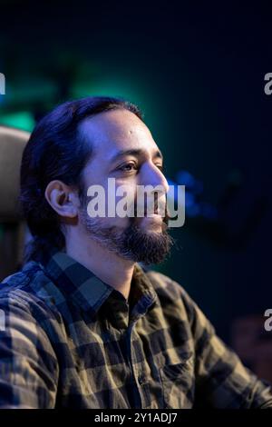 Side view profile of bearded man sitting on a chair. The image is showing a closeup shot of a positive male individual in a thoughtful gaze. Stock Photo