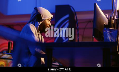 Hackers starting their day with coffee and music in headphones, ready to start hacking in underground bunker while using VPN and darknet as anonymity tools to mask their online identity Stock Photo