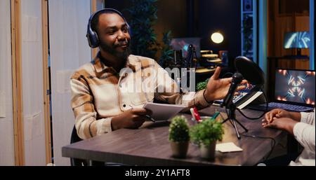 Show host talking with guest in studio, listening to opinion on current events, filming video for social media. Influencer presenting woman to audience before starting podcast Stock Photo