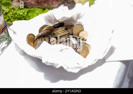 Gleaming Coins Resting in a White Cloth Pouch with Fresh Ingredients in Background. Stock Photo