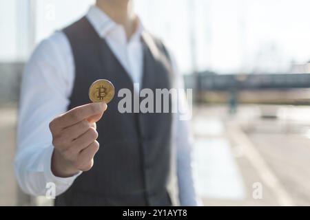 Bitcoin cryptocurrency coin in a young businessman hand. Disruptive blockchain technology concept and transfer of wealth Stock Photo
