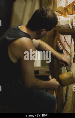 A craftsman uses tools to refine details on a wooden sculpture Stock Photo