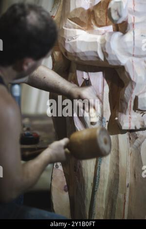 Close-up of an artist using a mallet and chisel on a wooden sculpture Stock Photo