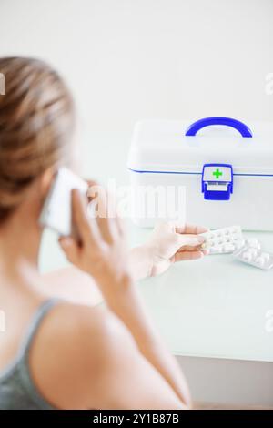 Woman calling to doctor. First aid kit on table Stock Photo