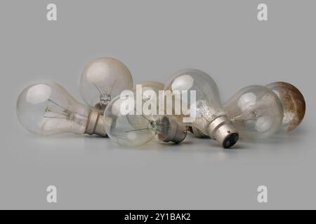 pile of old dirty or unusable burnt out incandescent light bulbs isolated gray background, discarded highly inefficient electric lamps Stock Photo