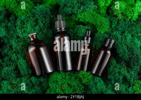 Brown glass dropper bottles arranged on green moss in a natural setting Stock Photo