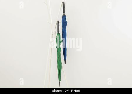 Colorful umbrellas on clothing rack against white background Stock Photo