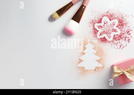 Christmas decorations made of powder and blush, gift box and makeup brushes on white background, flat lay. Space for text Stock Photo