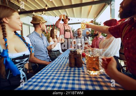 Group of friends, cheerful men and women raising beer mug in celebratory toast, having fun, leisure and enjoyment Stock Photo