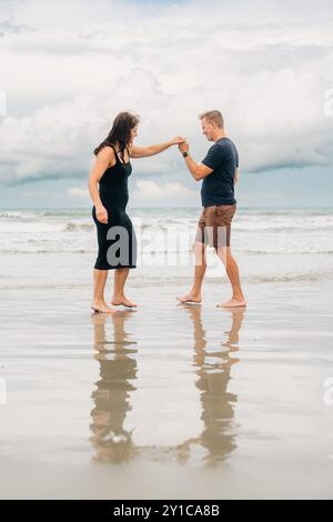 Couple dancing on the beach, holding hands Stock Photo