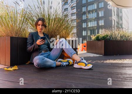 relaxed young woman using smartphone in urban outdoor setting Stock Photo