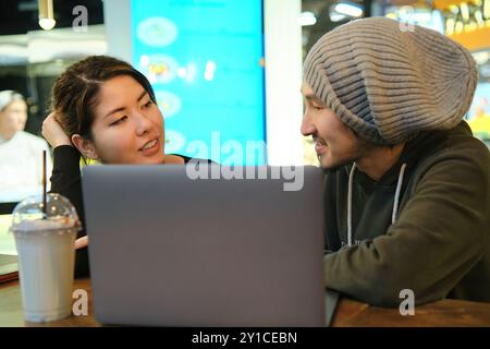 Asian couple sitting at a table in a restaurant and look at each Stock Photo