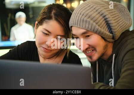 Asian couple sitting at a table in a restaurant and working with Stock Photo