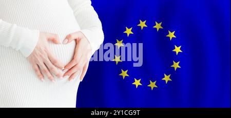 Demographics, pregnancy and love baby in EU concept. Pregnant woman making heart against her stomach on European Union flag background. Stock Photo