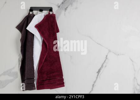 Set of Hanging Towels on Marble Bathroom Wall Stock Photo