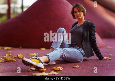 Relaxed young woman sitting among autumn leaves on red background Stock Photo