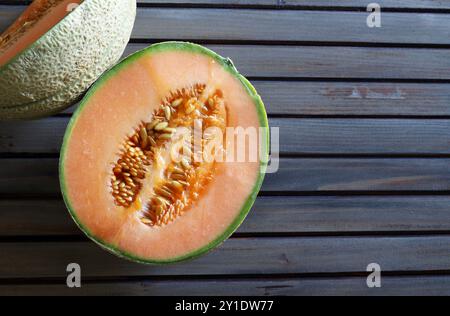 Cantaloupe melon cut in half isolated on a wooden table. Healthy and vegetarian food. Directly above. Copy space. Stock Photo