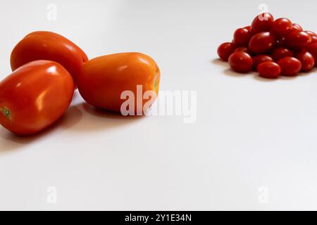 Three Italian tomatoes on the left of the image and a portion of cherry tomatoes on the right and out of focus. Stock Photo