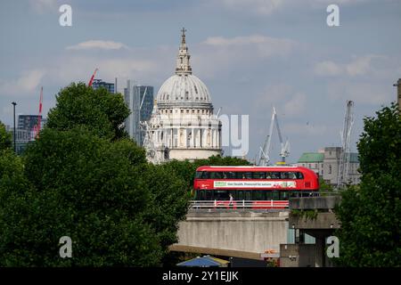 A New Routemaster double-decker bus, also known as a Boris bus crosses Waterloo Bridge over the River Thames, with the St. Paul’s Cathedral dome in th Stock Photo