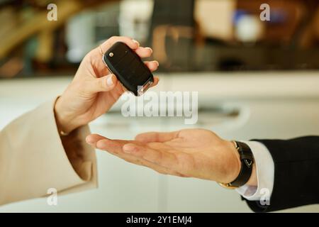 Close up on hand of female client giving smart key back to male agent at car rental office, copy space Stock Photo