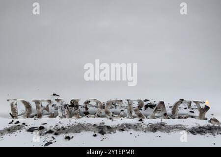 Wood letters spell out the word democracy against a white background.  The letters are burned and muddied, indicating that democracy is under attack. Stock Photo