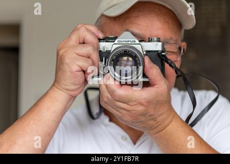 London. UK- 09.03.2024. A senior man using a vintage Olympus SLR camera. Stock Photo