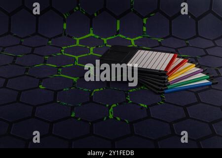 Colorful old floppy disks for old 16-bit and 8-bit 3.5-inch computers arranged on a black keyboard and mouse pad Stock Photo