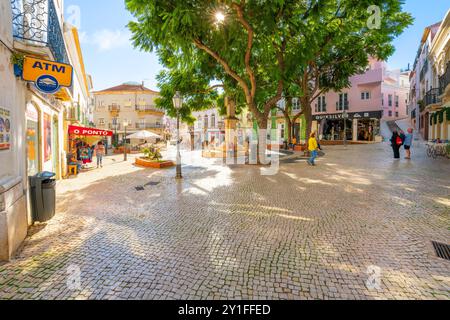 Pedestrians visit shops cafes on a sunny day at the Praça Luís de Camões town square in the Algarve city of Lagos, Portugal. Stock Photo