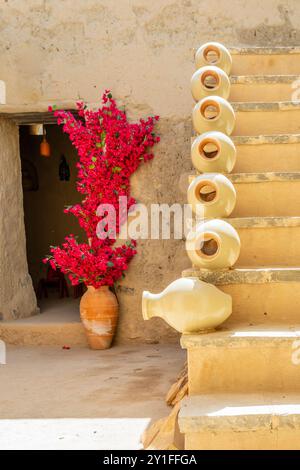 Pottery jugs decorating the stairs in arabic citadel fortress inner yard with flowers in the background, Bahla, sultanate Oman Stock Photo
