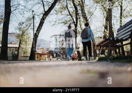 Two students walking together on a sunny campus pathway Stock Photo