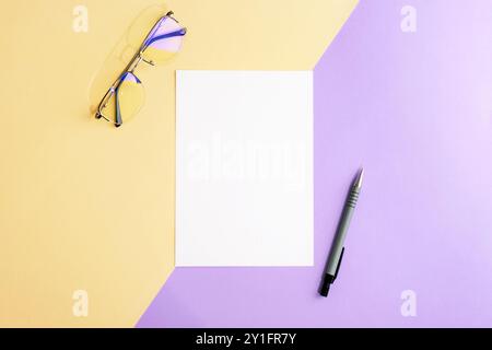 Desktop with blank paper, glasses and pen on beige and purple two-colored background. Top view, flat lay, mockup. Stock Photo