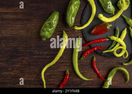 Pepperoni in different colours on and next to a dark plate, wooden base Stock Photo