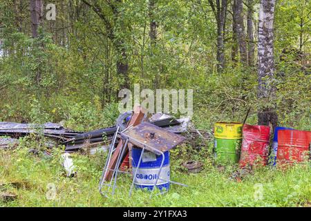 Environmental destruction with abandoned oil barrels and scrap metal in the forest Stock Photo