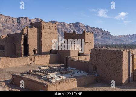 A traditional Berber village nestled in the foothills of the Atlas Mountains, with mud brick homes and palm groves dotting the landscape Stock Photo