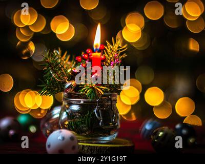Christmas Arrangement in a Glass Jar with Red Candle and Golden Bokeh Stock Photo